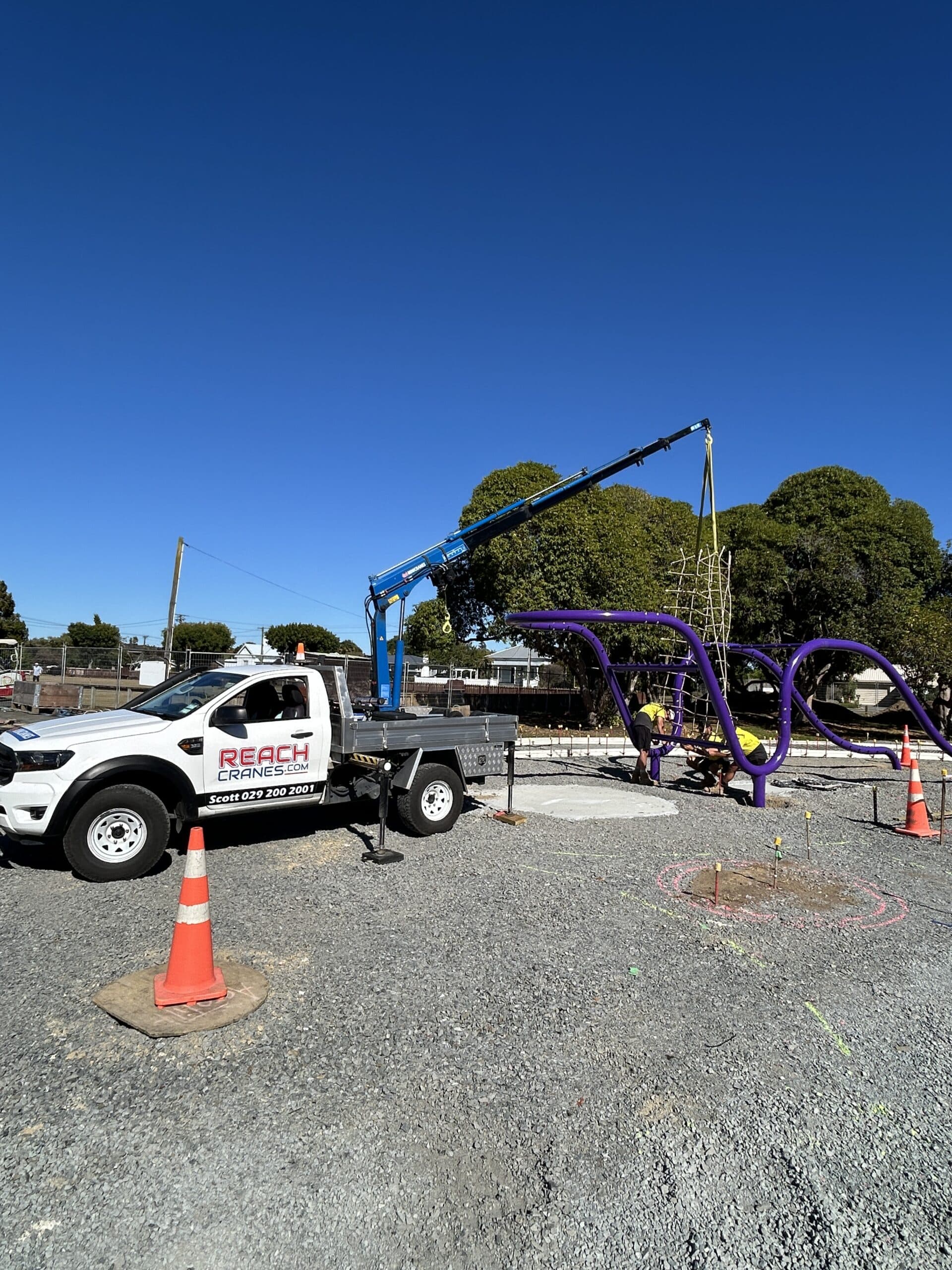 A Reach Cranes mini crane positioning a climbing frame for a new playground build with Playground Creations.