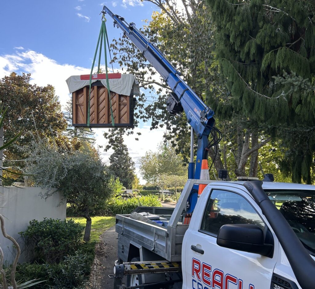 Reach Cranes lifting a piano over a wall