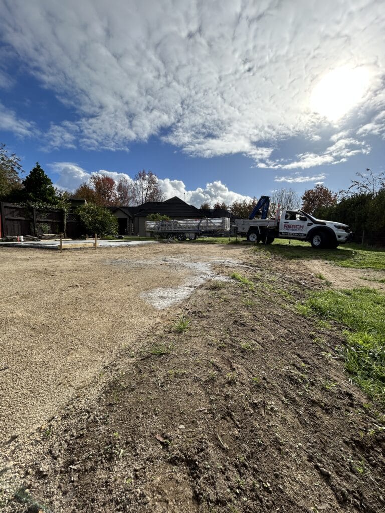 A Reach Cranes Hiab and trailer at a Tamahere home with a flat-packed one-tonne shed ready for placement beside a new foundation.